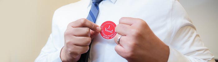 Voter placing an “I voted” sticker onto their shirt